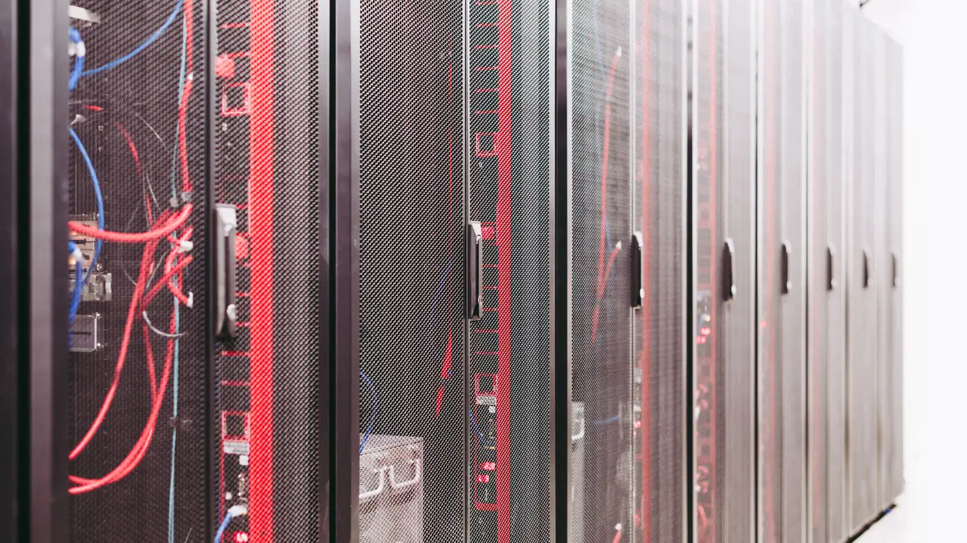 En række serverracks i et datacenter med røde og blå kabler