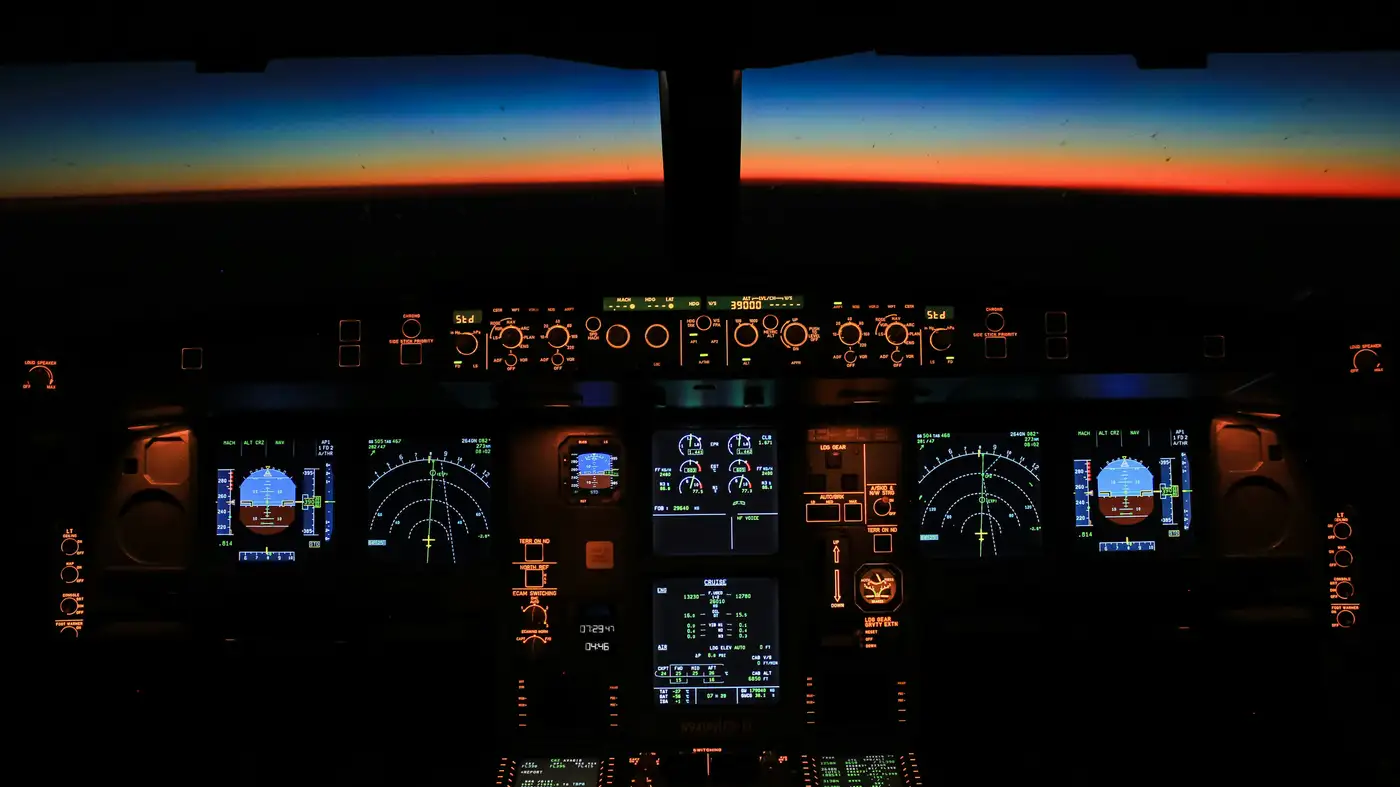 Et cockpitpanel i et passagerfly oplyst i skumringen