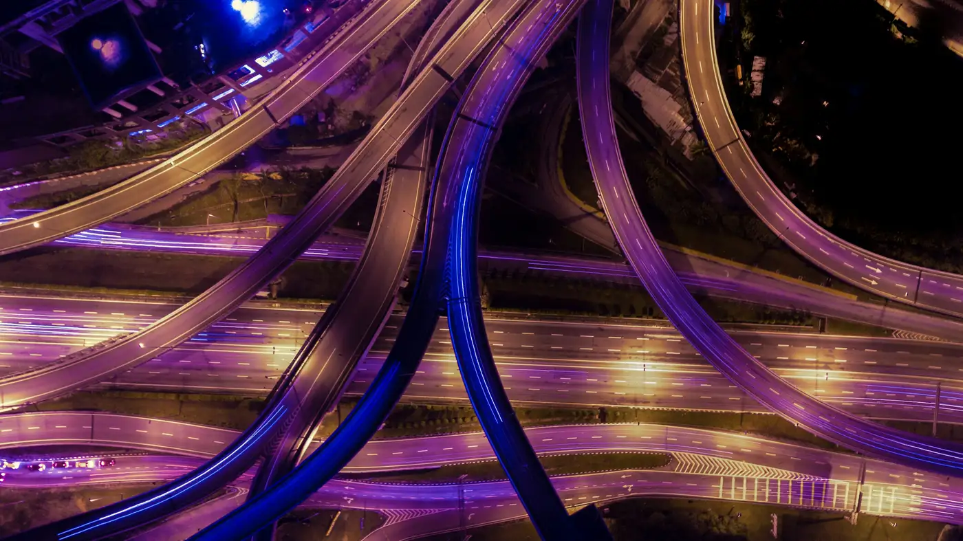 Et motorvejskryds i flere niveauer set oppefra om natten